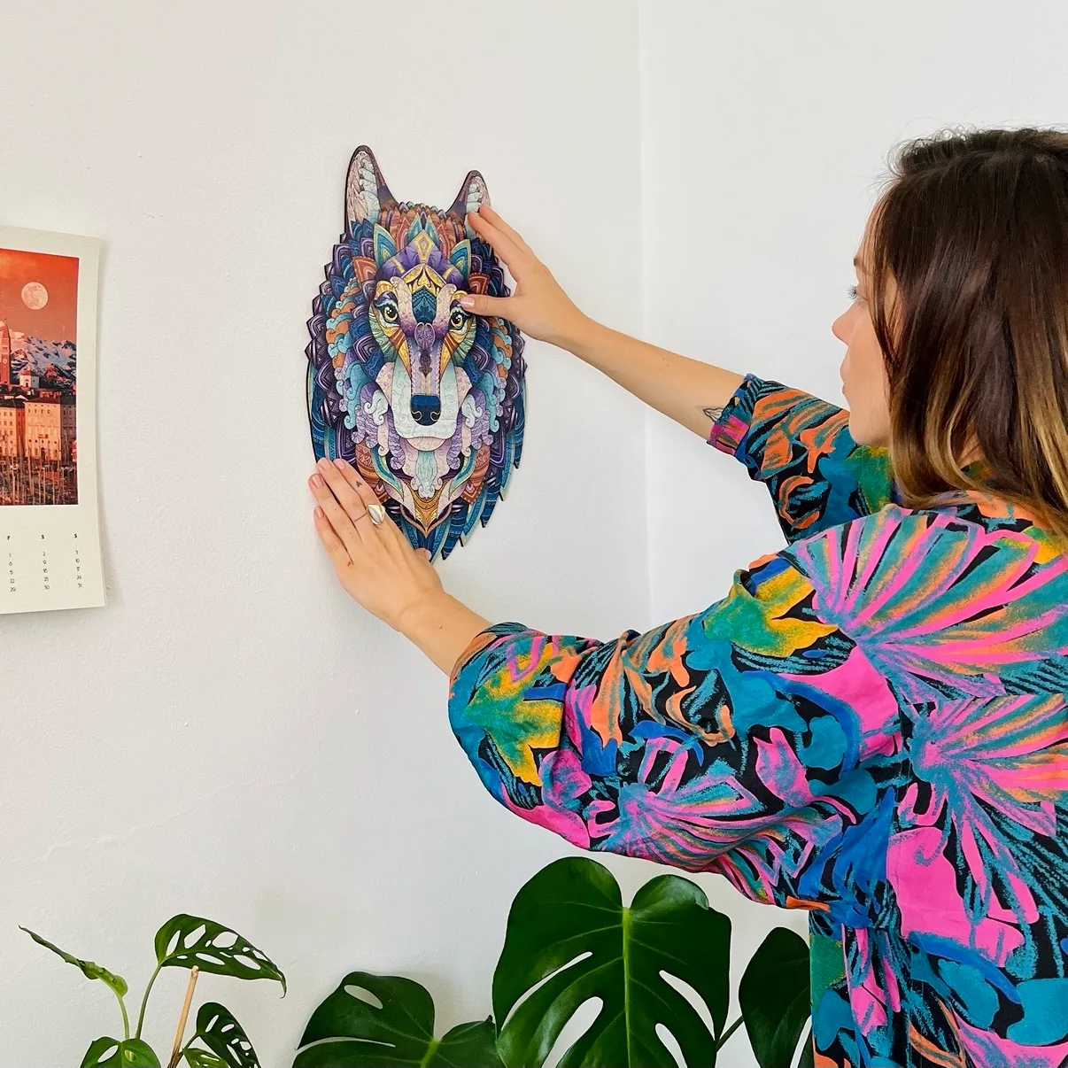 Woman hanging a colourful wooden animal puzzle on the wall